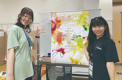 ポスターの前で案内するボランティア
